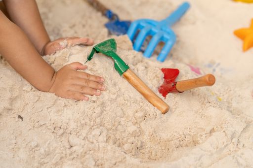 A top view of a child playing with beach toys on the sand