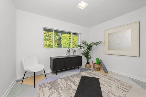 Minimalist room with a yoga mat, modern chair, and indoor plant by a window with a view of greenery.