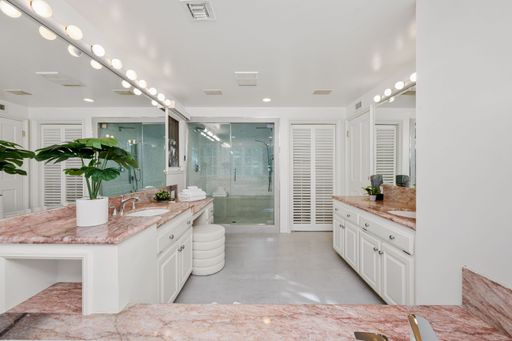 Luxurious modern bathroom with marble countertops, double sinks, and a large mirror reflecting elegant lighting and decor.