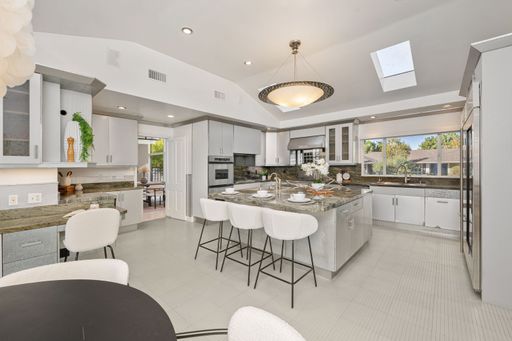 A modern kitchen interior with sleek design, with a large island, white cabinetry, and natural light
