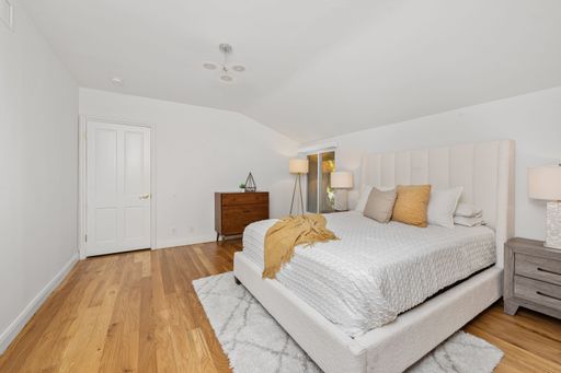 A modern bedroom interior with a cozy bed, wooden floor, and warm lighting