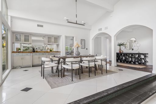 A modern dining room with elegant decor, featuring large windows and lush greenery