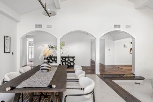 A modern dining room with elegant decor, featuring large windows and lush greenery