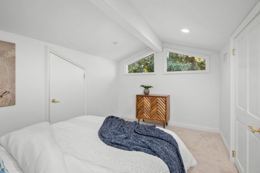 A modern bedroom interior with a cozy bed, wooden floor, and warm lighting
