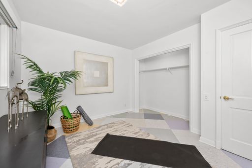 A minimalist home gym setup with yoga mat, plants, and decor in a bright room