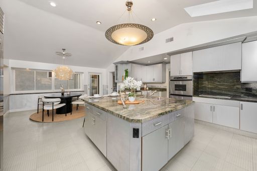A modern kitchen interior with sleek design, marble island, and elegant lighting