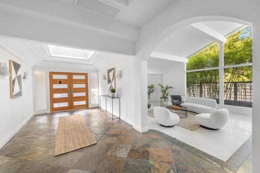 A modern living room with stylish furniture and large windows with lush greenery