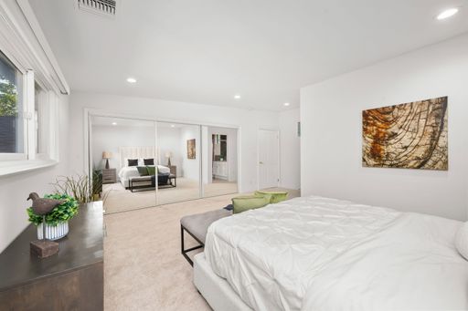 A modern bedroom interior with a cozy bed, wooden floor, and warm lighting