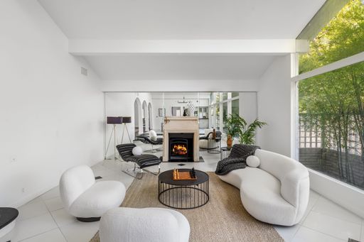 A modern living room with white furniture, fireplace, and open layout