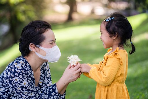 A cute happy Asian small girl giving her mother an Indian cork flower in a park