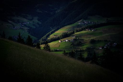 A beautiful shot of grassy hills near grassy fields with trees and buildings in the distance