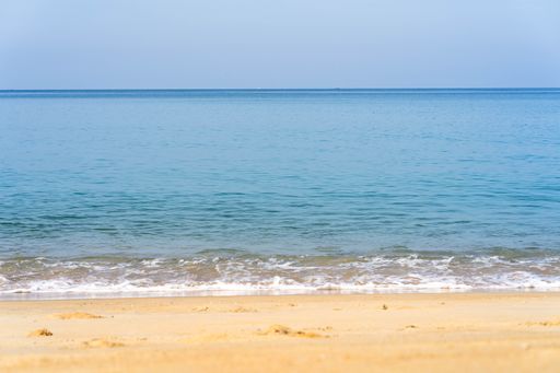 A beautiful shot of foam waves hitting a sandy seashore on a sunny day