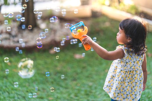A back view of a cute Thai girl playing with soap bubbles