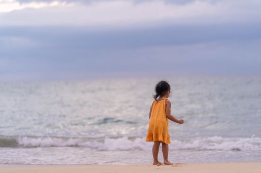 A back view of a cute little Thai girl at the beach