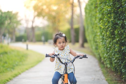 A cute little Thai girl riding a bicycle in a park