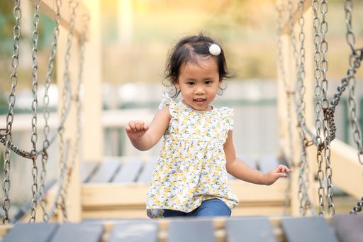 An adorable Thai girl running over a metal construction in the park