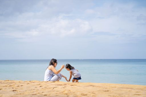 Young Thai mother and daughter playing at the seashore