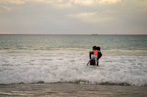 An active young mother and daughter in swimming suit playing at the beach