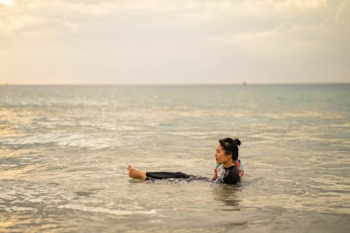 A closeup shot of a Southeast Asian female lying in the sea under sunlight