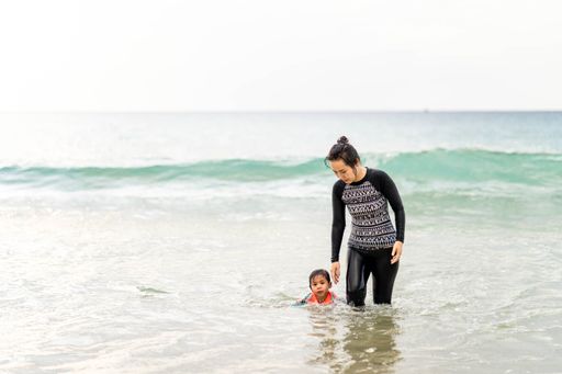 An active young mother and daughter in swimming suit playing at the beach