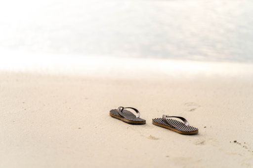 A close-up shot of flip-flops on the beach background.