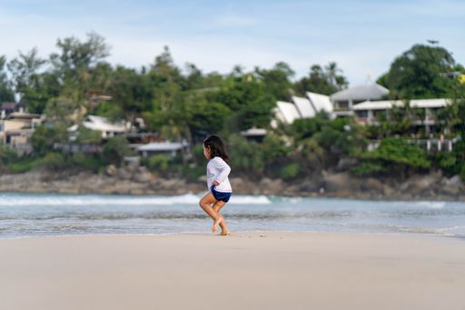 A southeast asian female kid running on the beach