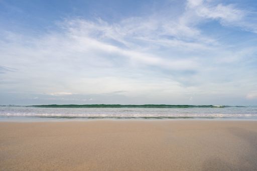 A beautiful view of a beach with a wavy sea under the blue sky