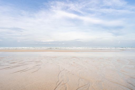 A high angle shot of a sandy beach with beautiful seascape and skyline melded together