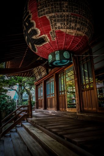 A vertical shot of red lantern over the stairs near the wooden Japanese style house