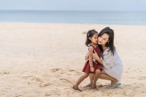 A Southeast Asian mother and her daughter having a great time on the beach in Thailand