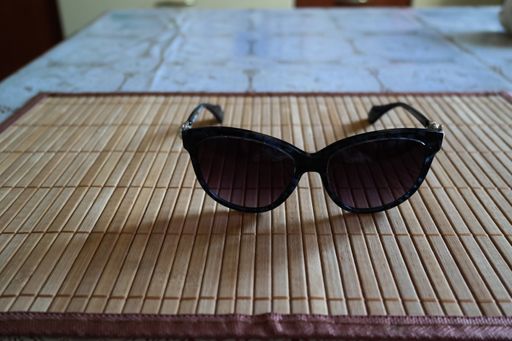 A closeup shot of black sunglasses on a wooden surface on a table