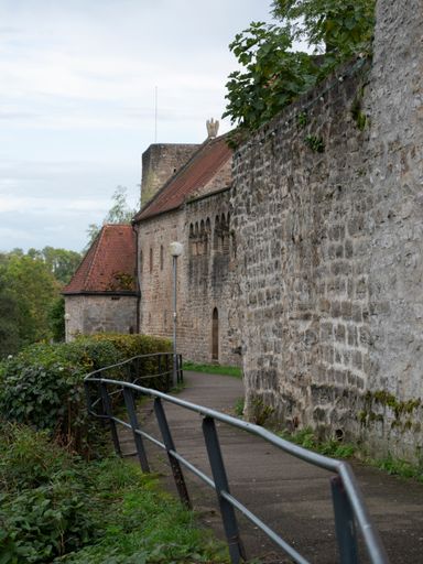 A medieval caste wall near the bushes under the cloudy sky