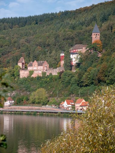 A castle on a green hill with the lake against it on a sunny day