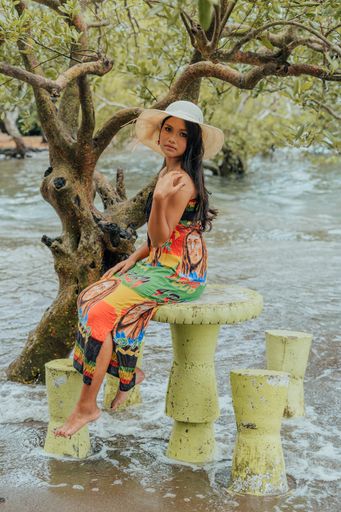 A beautiful young woman wearing a dress and hat posing outdoors