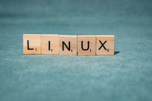 Wooden letter tiles spelling 'LINUX' on a green textured background, symbolizing open-source software and technology.