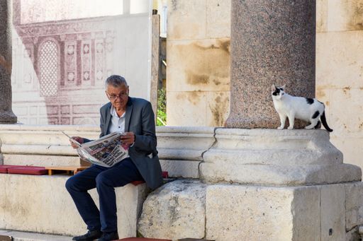 Candid image of senior reading newspaper in public.