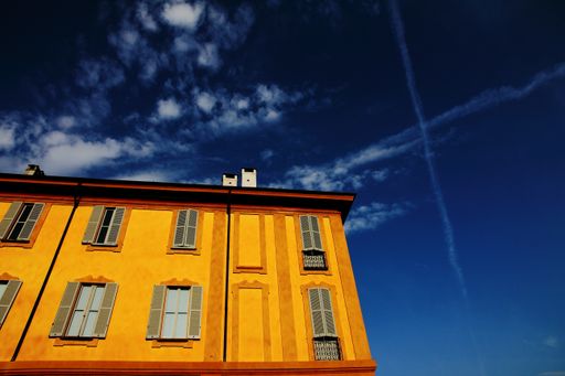 A low angle shot of a yellow house with windows under the blue sky