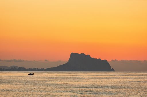 A beautiful view of the sunset over the hill and the ocean on a summer day