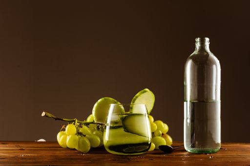A closeup shot of grapes a bottle of oil on the table