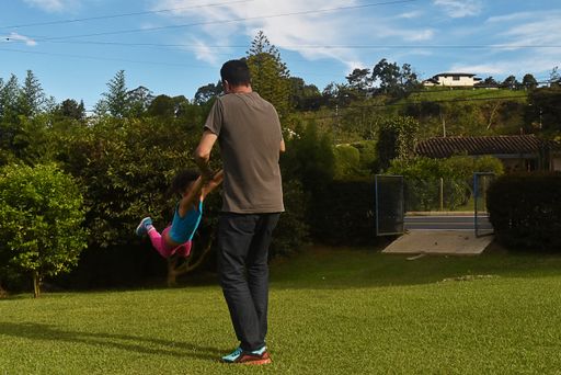 A dad playing with his child by holding from his hands