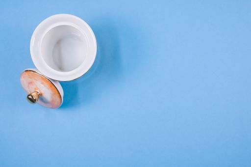 A top view of an orange empty cup next to a cover on a blue isolated background with free space