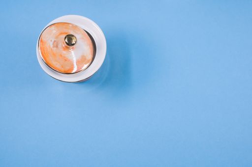 A top view of an orange covered ceramic cup on a blue isolated background with free space