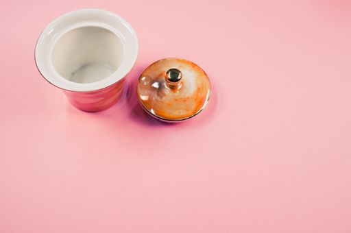 A top view of an orange empty cup next to a cover cup on a pink isolated background with free space
