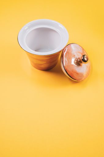 A top view of an orange empty cup next to a cover cup on an orange isolated background with free space
