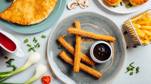 A top view of a plate of fresh churros served with chocolate sauce
