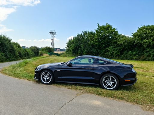 A black Ford Mustang model 2018 at a country road in Germany