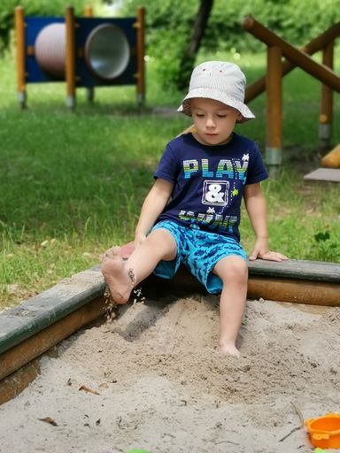 A shot of a little boy playing in the playground with sand