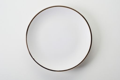 A top view of a white ceramic flat plate with a black rim on a white background