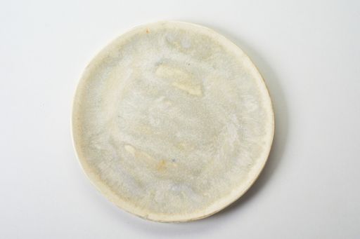 A top view of a rustic yellow ceramic flat plate on a white background