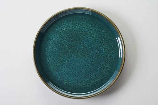 A top view of a blue ceramic flat plate on a white background